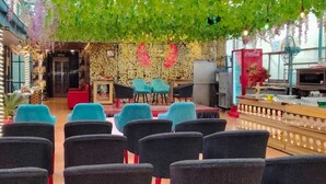 A restaurant with a stage, seating area, and a Coca-Cola refrigerator. - Le-Leisure Hotel (Prayagraj)