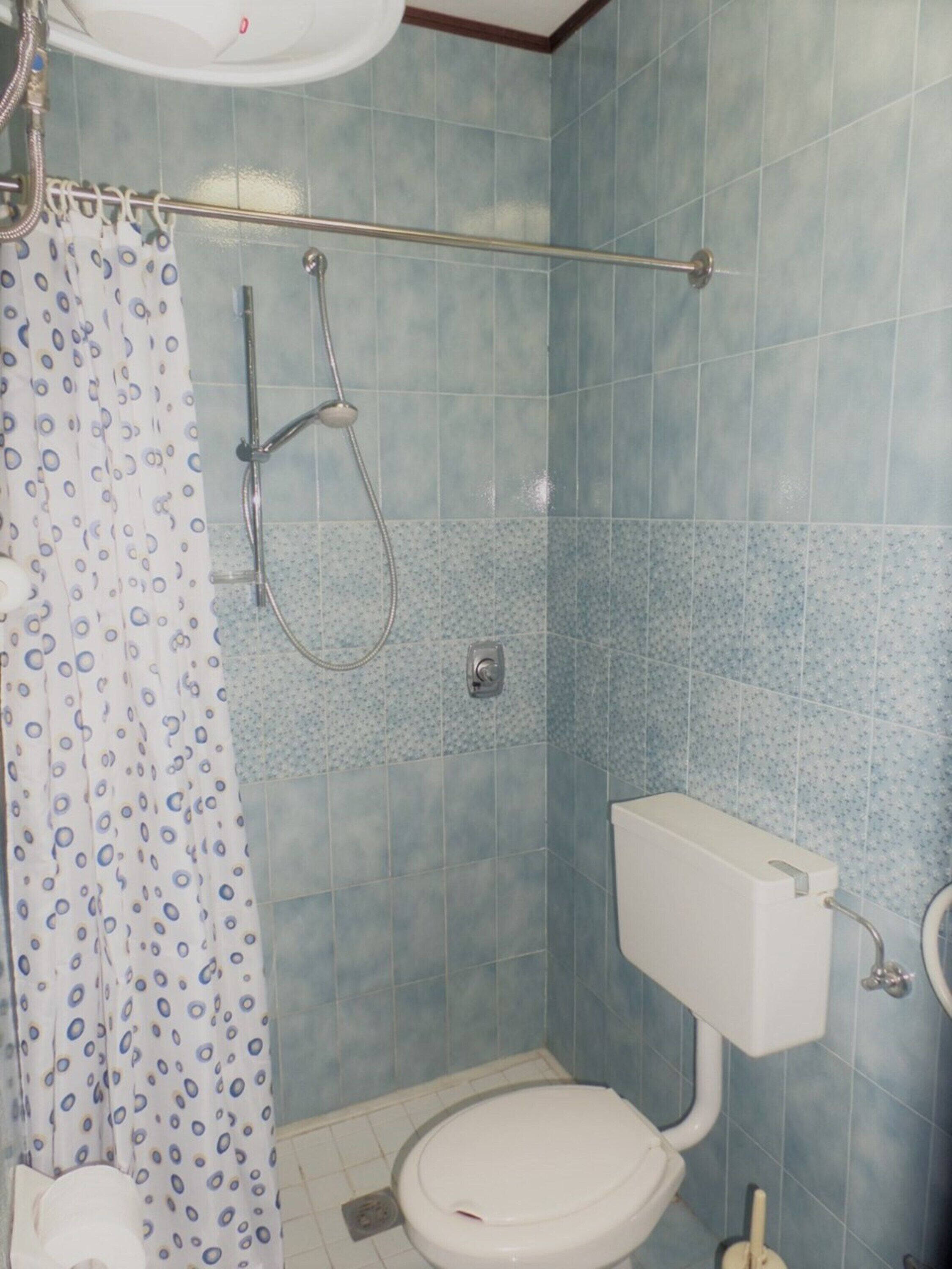 A bathroom with a shower, toilet, and sink.