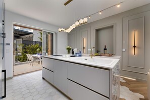 A modern kitchen with a large island, a built-in oven, and a dining area with outdoor seating. - Deluxe 2 bedroom apartment Azzura with swimming pool and sea view (Malinska)
