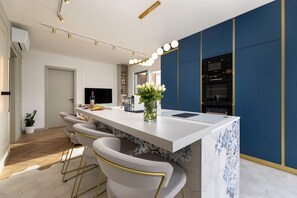 A modern kitchen with a central island, bar stools, a dining area, and a built-in oven. - Deluxe 2 bedroom apartment Azzura with swimming pool and sea view (Malinska)