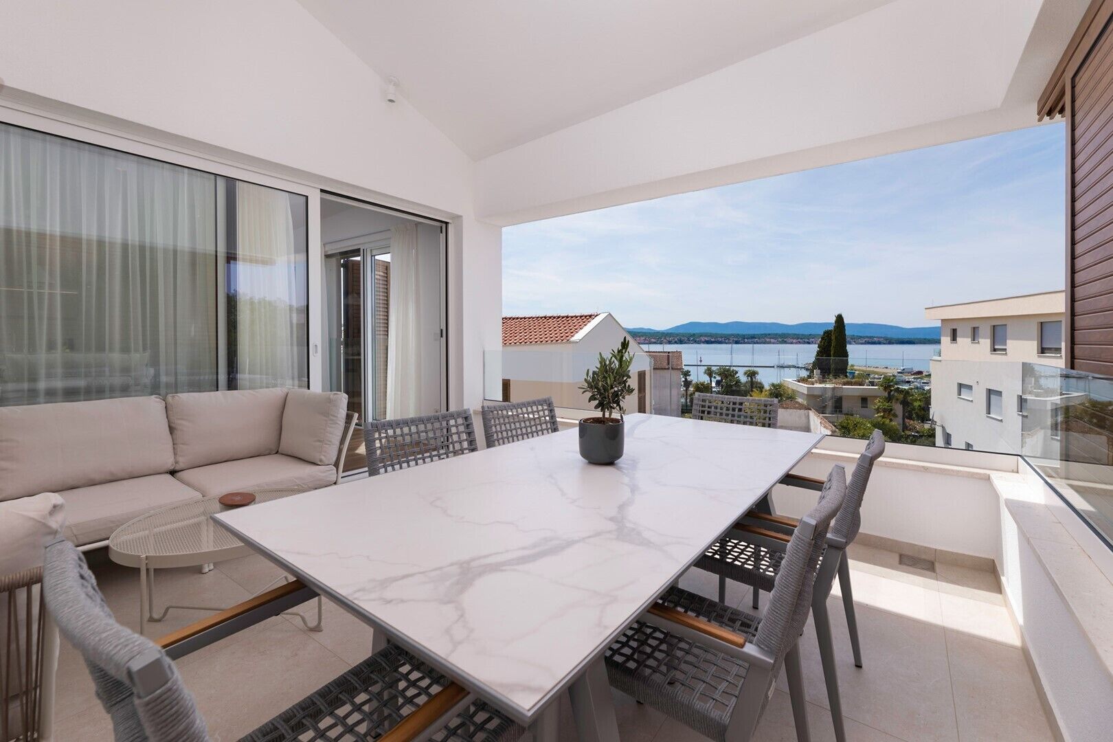 Ein Balkon mit weißem Tisch, Stühlen und einer Sitzecke.