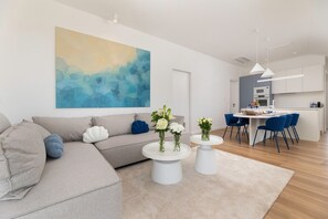 Ein modernes Wohnzimmer mit einer Couch, zwei Couchtischen und einem großen abstrakten Gemälde.