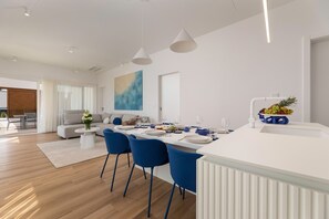 Eine moderne Küche mit Essbereich, weißen Schränken und blauen Stühlen.
