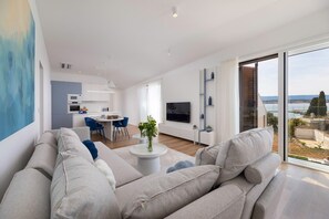 Uma sala de estar moderna com sofá, área de refeições, cozinha e uma janela ampla com vista.