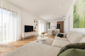 Ein modernes Wohnzimmer mit einer Couch, einem Fernseher und einem Essbereich.
