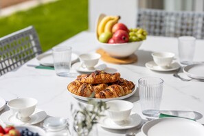 A table set with croissants, a fruit bowl, and white cups and saucers. - Deluxe Olive Apartment with three bedrooms, swimming pool, and sea view – ground floor (Malinska)