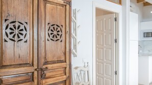 A wooden door with a geometric cut-out design, a white door with a decorative metal frame, and a white wall with a small decorative item. - Apartment 'Casco Antiguo Sirocco' with Wi-Fi and Air Conditioning (Tarifa)