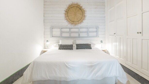 A bedroom with a bed, a wall-mounted shelf, and a large wardrobe. - Apartment 'Casco Antiguo Sirocco' with Wi-Fi and Air Conditioning (Tarifa)