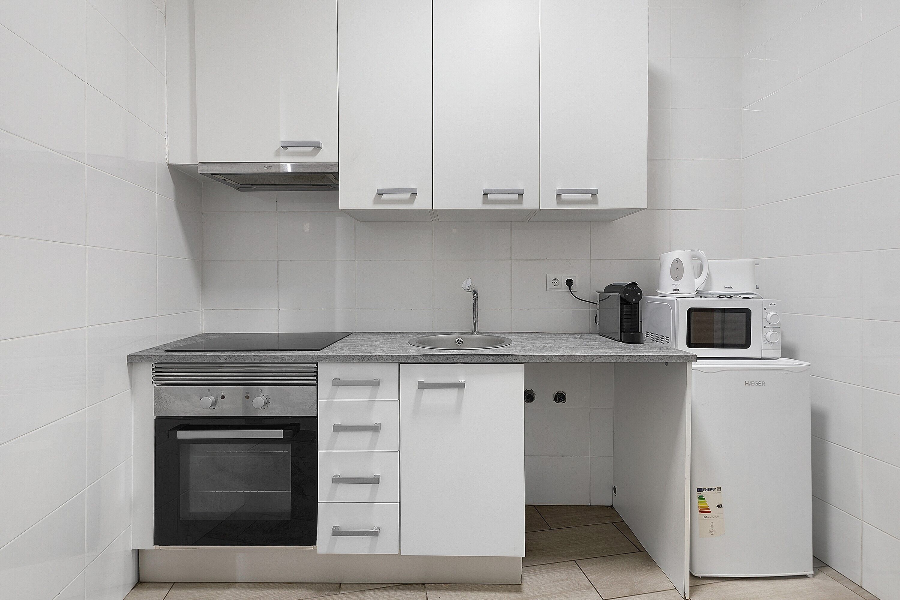 A compact kitchen with a stove, oven, microwave, and refrigerator.