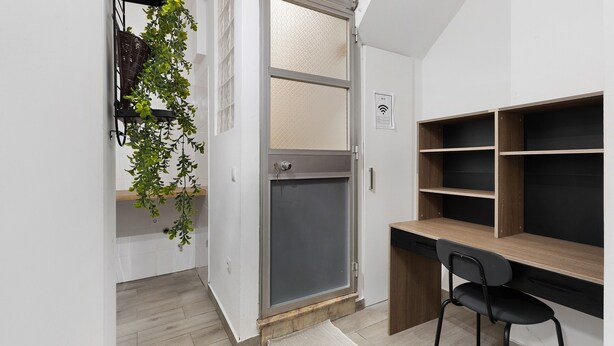 A room with a desk, chair, shelving, a door with a screen, and a plant. - Lisbon Apartment – Excellent Central Location (Lisbon)