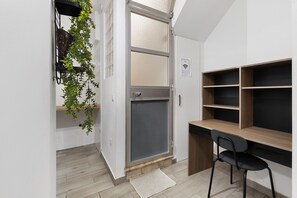 A room with a desk, chair, shelving, a door with a screen, and a plant. - Lisbon Apartment – Excellent Central Location (Lisbon)