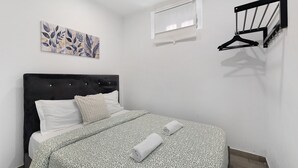 A bedroom with a bed, a wall-mounted light, a window, and a wall art piece. - Lisbon Apartment – Excellent Central Location (Lisbon)