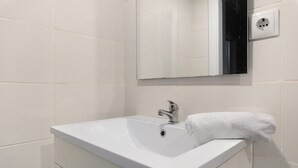 A bathroom with a white sink, a mirror, and a towel. - Lisbon Apartment – Excellent Central Location (Lisbon)