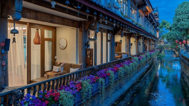 A traditional building with a waterway, wooden balconies, and hanging decorations. - Cloudland Skystream View Designer Inn (Lijiang)