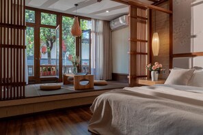 Un dormitorio con un gran ventanal, muebles de madera, una cama y una lámpara colgante.