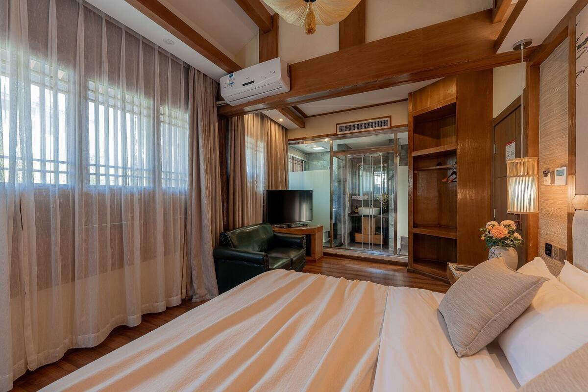 A hotel room with a bed, a TV, a closet, and a shower area.