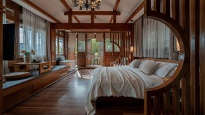 A bedroom with a large bed, wooden beams, a chandelier, and a view through a wooden-framed window. - Cloudland Skystream View Designer Inn (Lijiang)