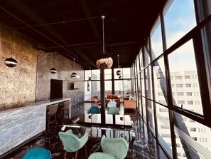 Ein modernes Interieur mit Bar, Sitzgelegenheiten und großen Fenstern mit Blick auf die Stadt.
