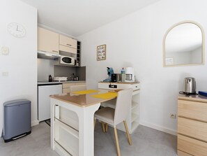 A compact kitchen with a microwave, coffee maker, and a small trash bin. - Air-conditioned studio for 2 people, near the shops (Grasse)