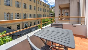 A balcony with a table and chairs, overlooking a cityscape with historic buildings. - Air-conditioned studio for 2 people, near the shops (Grasse)