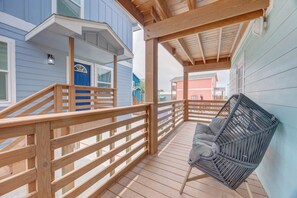 A wooden deck with a railing, a blue door, and a gray chair. - CL3 Shared Pool, Charcoal Grill, Old Town Port A (Port Aransas)