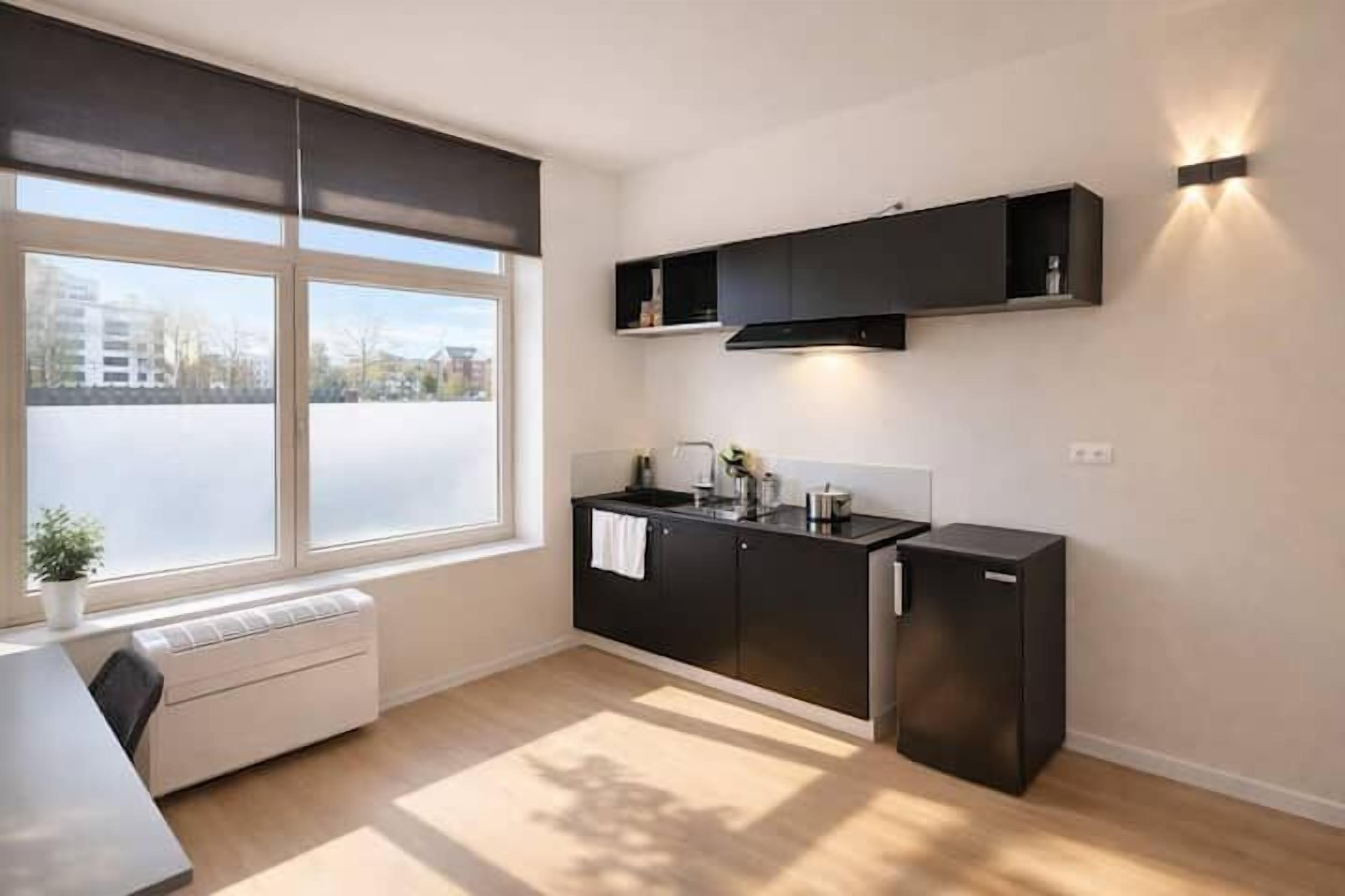 A modern kitchen with a window, built-in cabinets, a countertop, and a refrigerator.