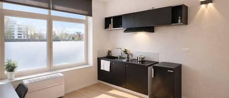 A modern kitchen with a window, built-in cabinets, a countertop, and a refrigerator.