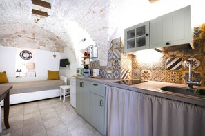 A compact kitchen with a stone arch ceiling, a built-in bench, and a tiled backsplash. - Cozy apartment on two levels that accommodate up to 3 people and is equipped with all the main comforts for a pleasant stay. The location is excellent, in the center, with all the essential services at hand and a short distance from the points of interes (Martina Franca)