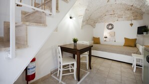 Une pièce chaleureuse avec un escalier, une table à manger, un canapé et un téléviseur.