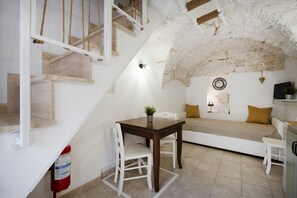 A cozy room with a staircase, a dining table, a sofa, and a television. - Cozy apartment on two levels that accommodate up to 3 people and is equipped with all the main comforts for a pleasant stay. The location is excellent, in the center, with all the essential services at hand and a short distance from the points of interes (Martina Franca)