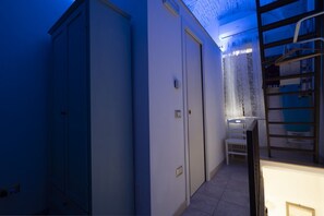 A narrow hallway with a door, a small table with a chair, and a ladder leaning against the wall. - Cozy apartment on two levels that accommodate up to 3 people and is equipped with all the main comforts for a pleasant stay. The location is excellent, in the center, with all the essential services at hand and a short distance from the points of interes (Martina Franca)