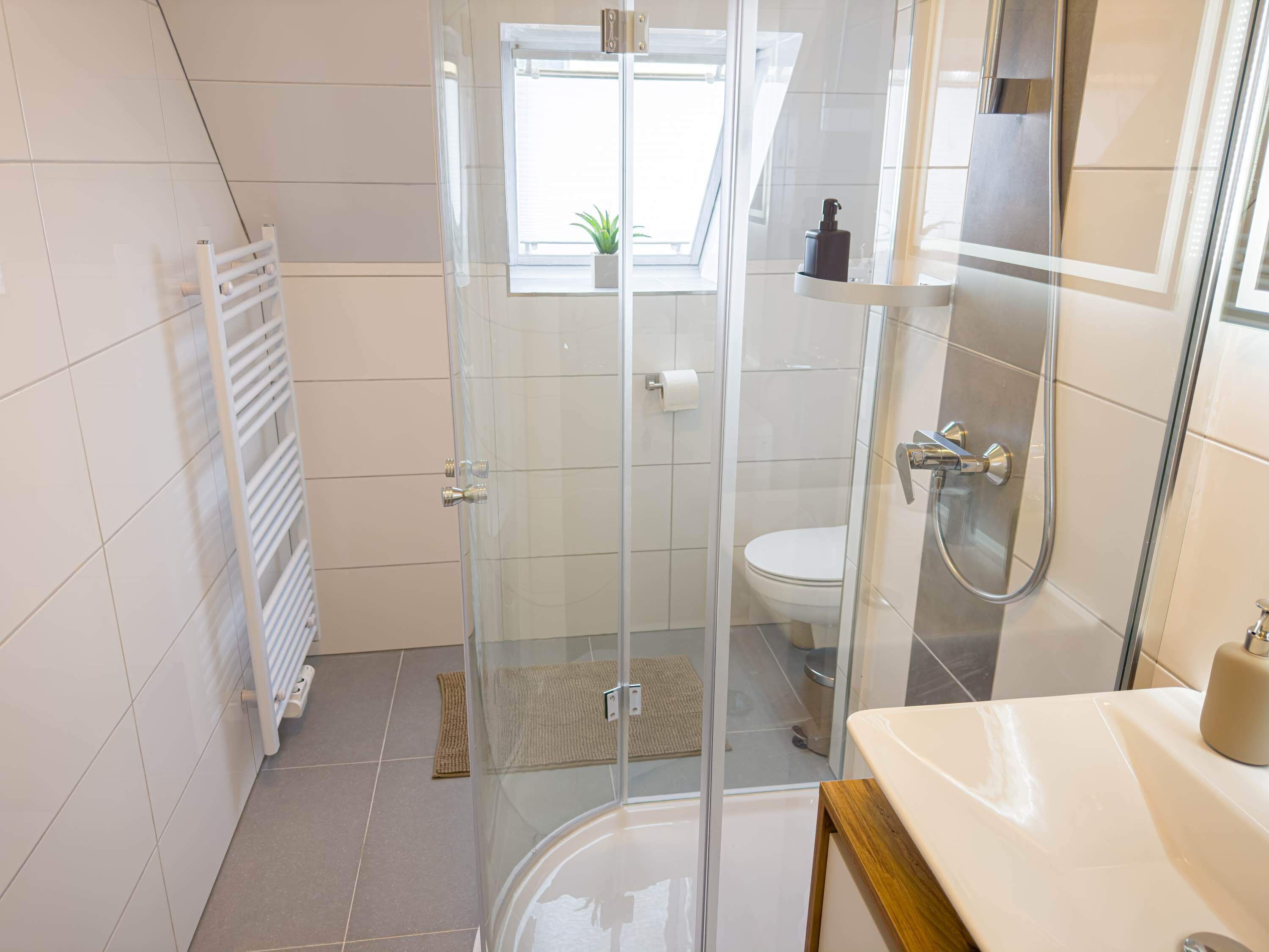 Une salle de bain moderne avec une douche à parois de verre, des toilettes et un lavabo avec un miroir.
