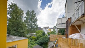 A residential area with a yellow building, a wooden deck, and a view of neighboring houses and trees. - Marßeler Str. 21 (Bremen)