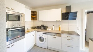 A modern kitchen with built-in appliances, a washing machine, and a coffee maker. - Marßeler Str. 21 (Bremen)