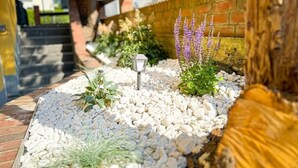 A garden pathway with white pebbles, a brick wall, and a wooden fence. - Marßeler Str. 21 (Bremen)