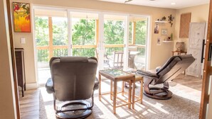 A spacious living room with a large sliding glass door leading to a deck, a ceiling fan, and a fireplace.