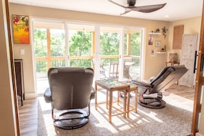 A spacious living room with a large sliding glass door leading to a deck, a ceiling fan, and a fireplace.