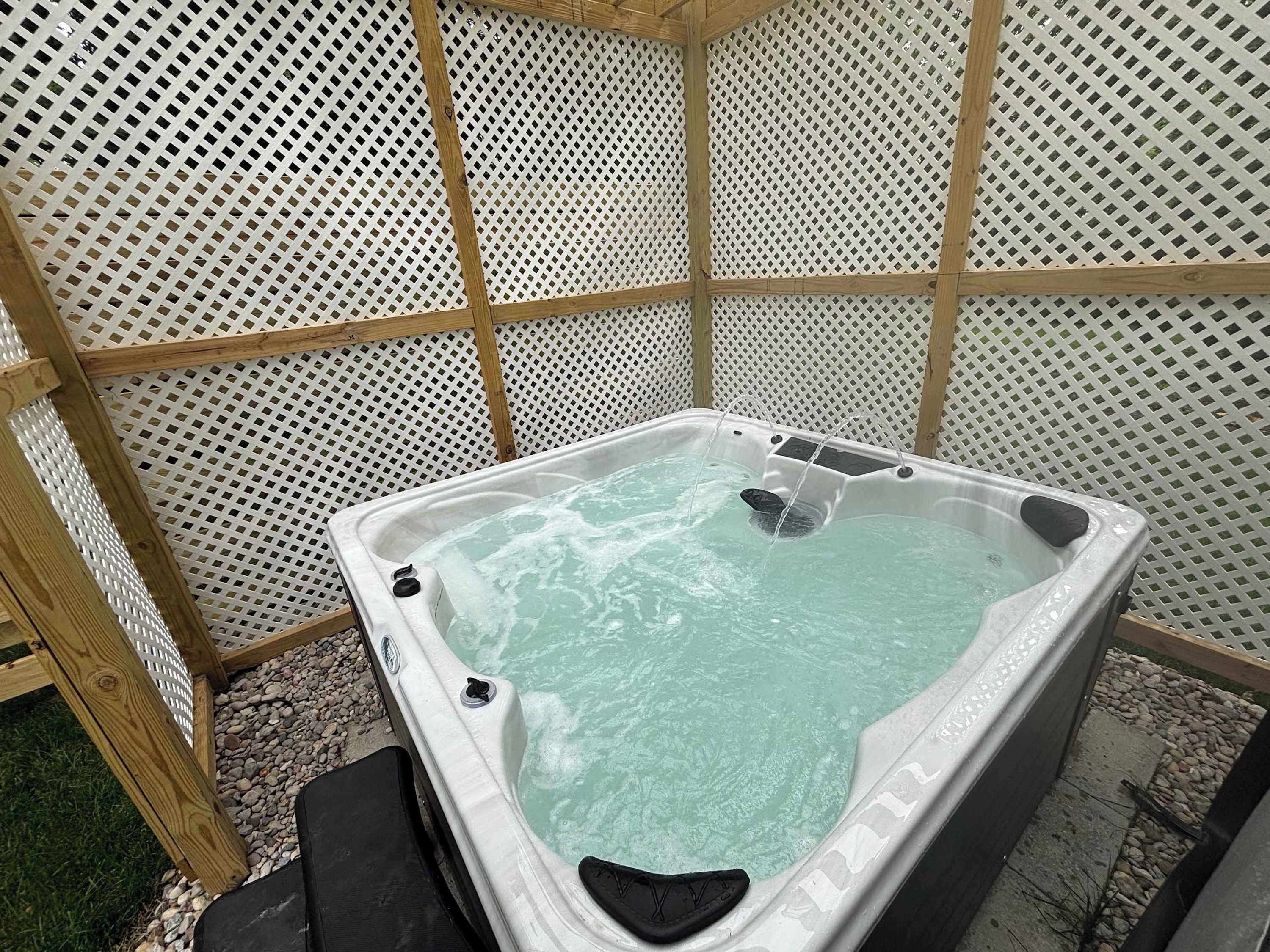 A hot tub with a wooden frame and a white lattice wall.