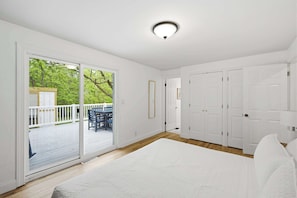 A bedroom with a large bed, sliding glass doors to a balcony, and a white ceiling light. - Mason Ranch - Game Room w/ Hot tub (Mason)
