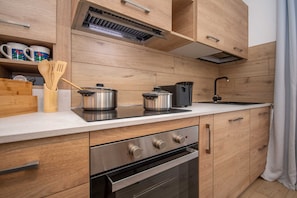 A modern kitchen with wooden cabinetry, stainless steel appliances, and a built-in oven.