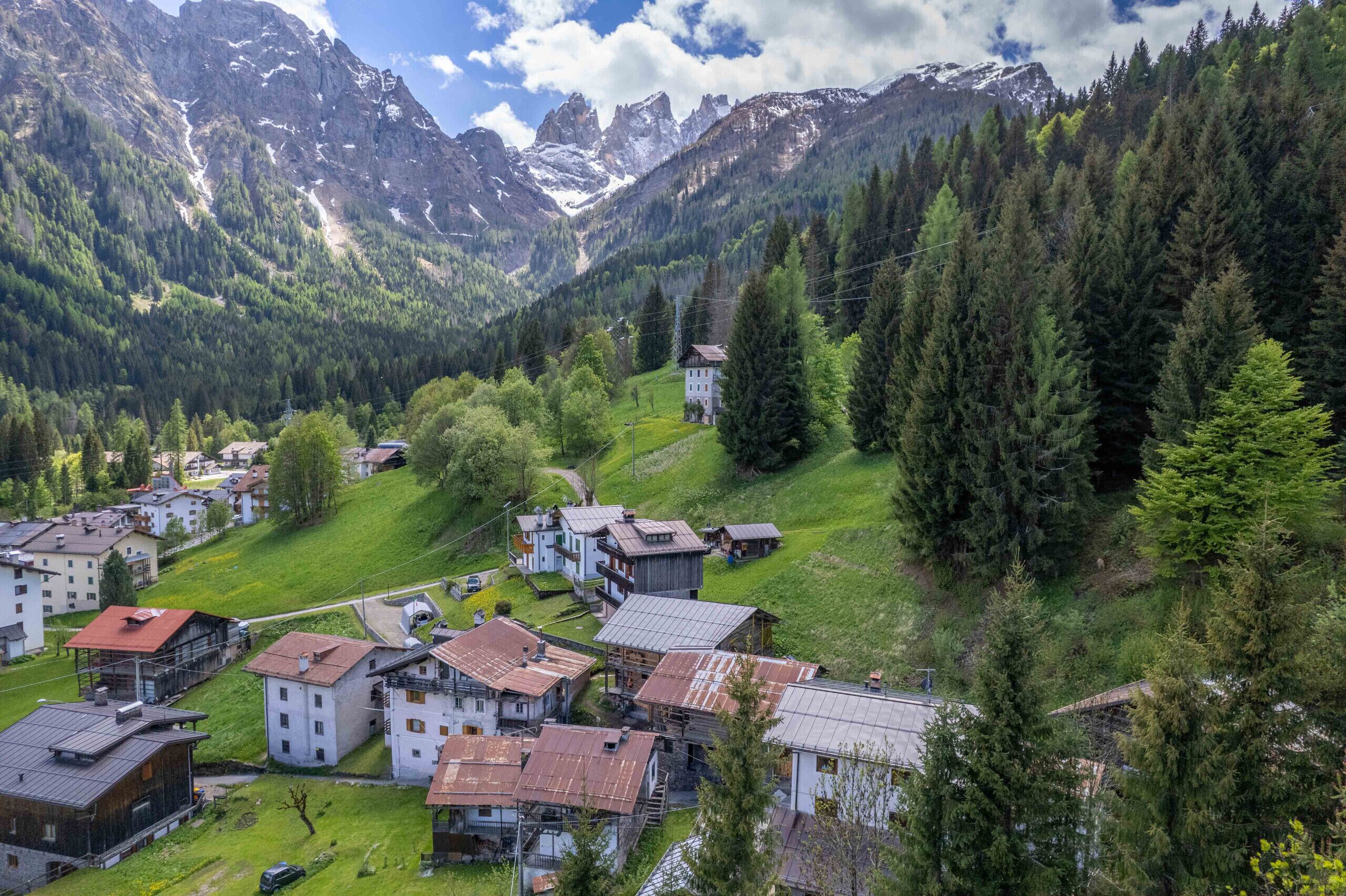 A mountainous village with traditional buildings, a small church, and a clear view of the surrounding peaks.
