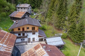 A multi-story house with a balcony, surrounded by trees and a hilly landscape. - Suite Mas de Le Mole (Falcade)