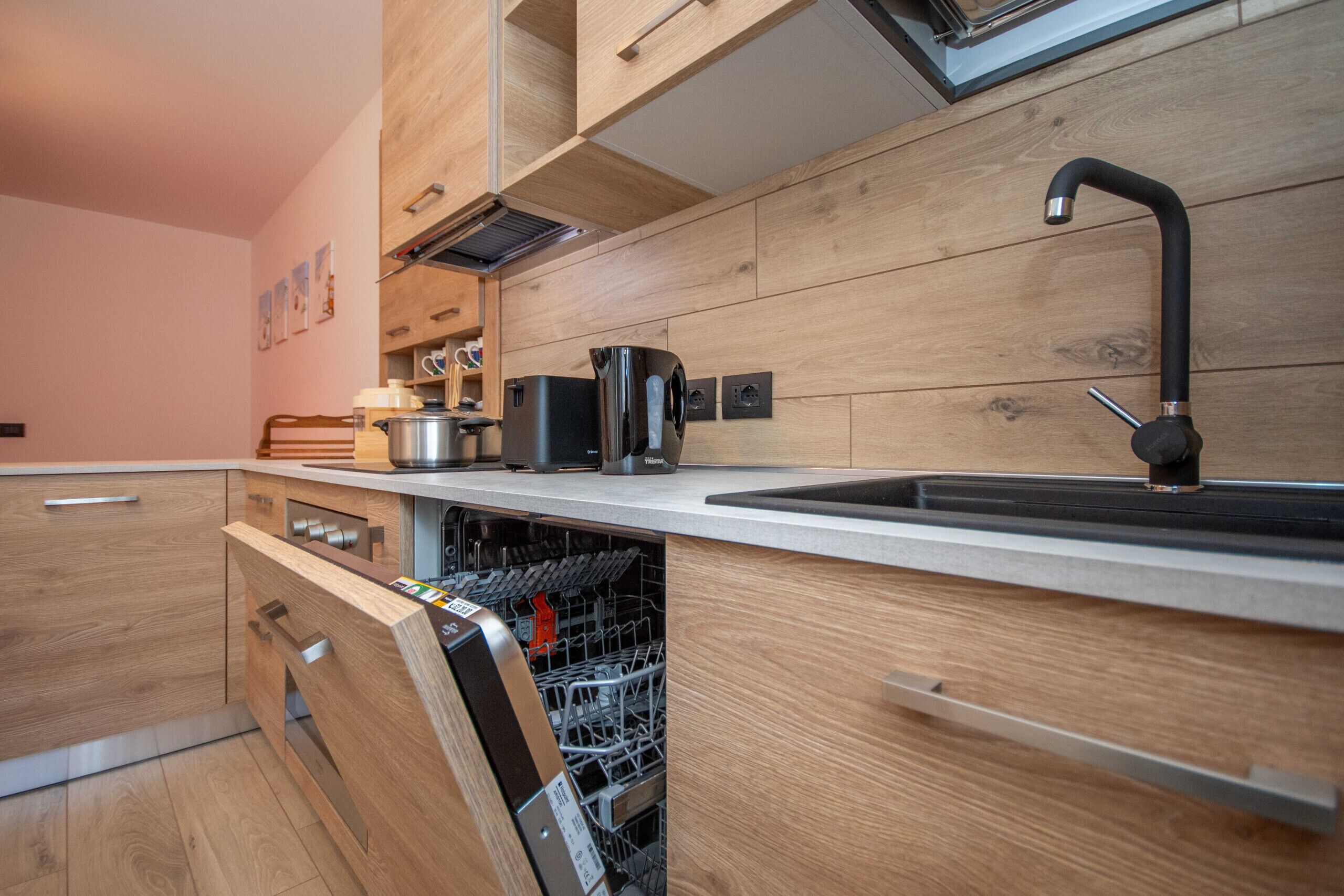 A modern kitchen with wooden cabinetry, a stainless steel dishwasher, and a black faucet.