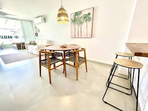 Una sala de estar moderna con comedor, una lámpara colgante y un aire acondicionado instalado en la pared.