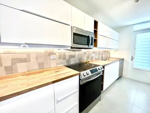 A kitchen with white cabinets, a microwave, a stove, and a dishwasher. - CoCo Beachfront self check-in, pool and parking (Dorado)