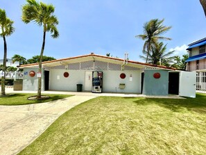 A building with a red-tiled roof, a white facade, and a small front garden. - CoCo Beachfront self check-in, pool and parking (Dorado)