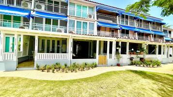 A multi-story hotel with balconies, a covered front porch, and a well-maintained lawn.