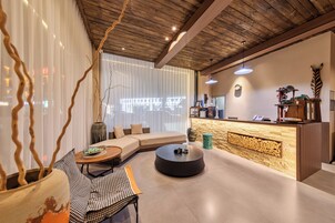 Interior moderno com teto de madeira, um sofá, mesa de centro redonda, uma pequena mesa de jantar e um balcão de recepção.