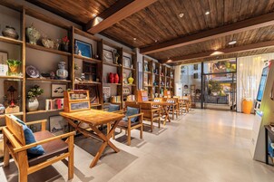 Um interior acolhedor com móveis de madeira, prateleiras com objetos decorativos e vista através de portas de vidro.
