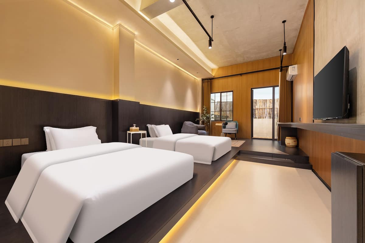 A modern hotel room with a large bed, a sofa, a TV, and a small table.